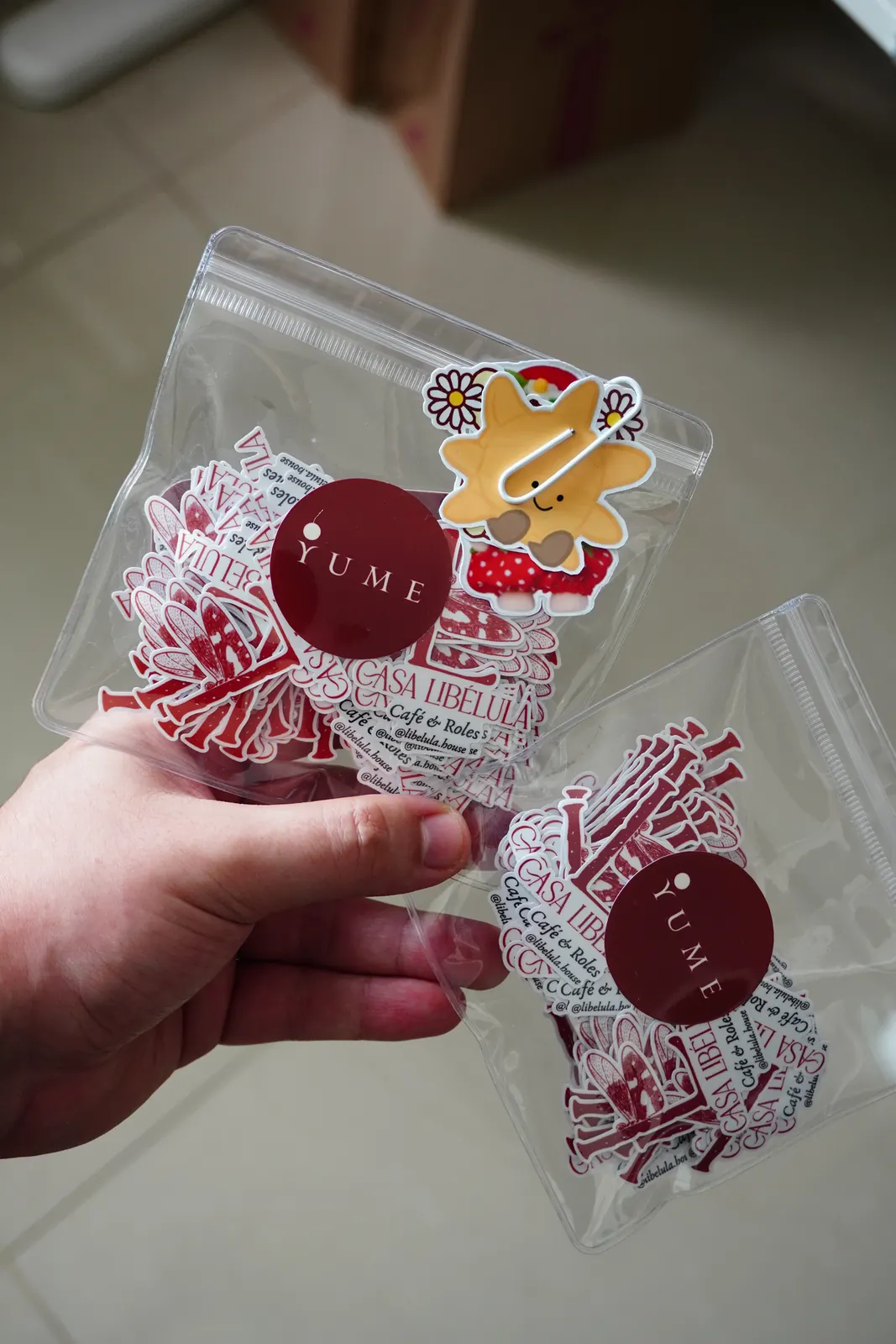 Bolsitas transparentes con stickers de logo, un sticker extra de regalo y la etiqueta redonda burdeos de Yume