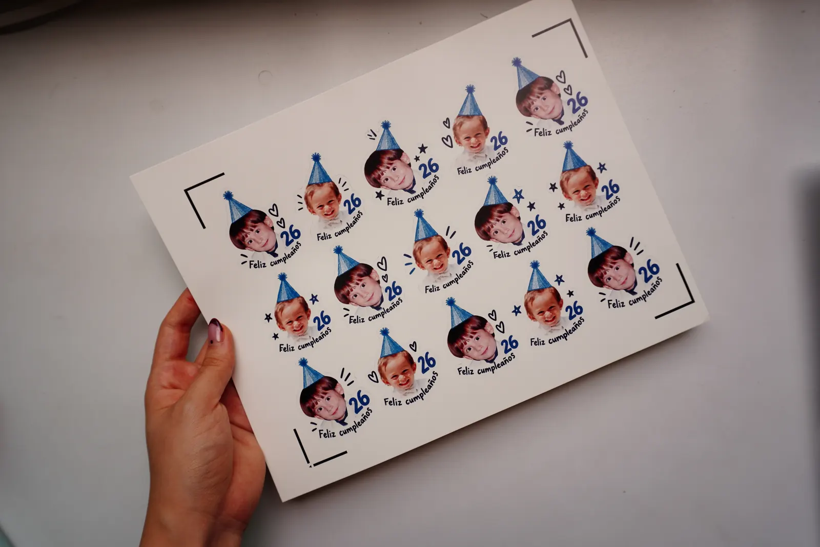 Mano sosteniendo una hoja de tatuajes temporales de cumpleaños con fotos de infancia